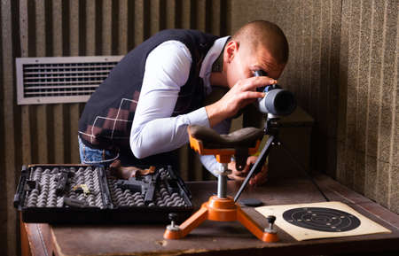 Instructor of shooting range looks through spyglass at targetの写真素材