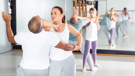 Active woman with professional trainer are training captures on the self-defense course in gym