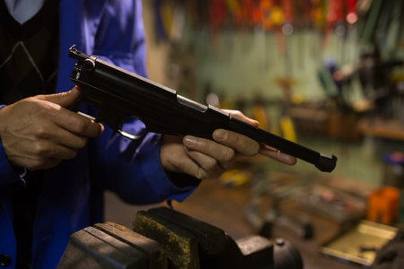 Gun repairman disassembling sporting handgun before preventive maintenance