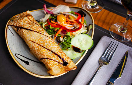 Appetizing savory stuffed thin pancake with vegetable saladの写真素材