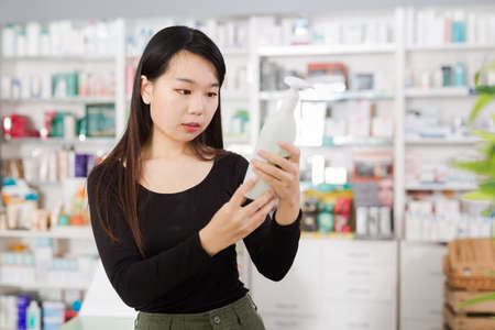 Young chinese woman chooses antibacterial at the pharmacyの写真素材