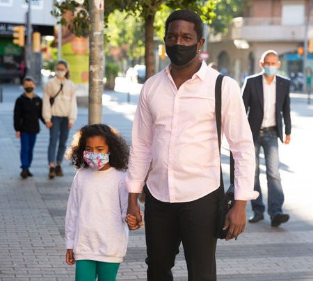 Father with daughter in protective face mask for spreading of virus disease prevention walking on streetの写真素材