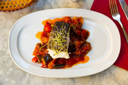 cuisine spanish candied fish with stewed vegetables served on white plate