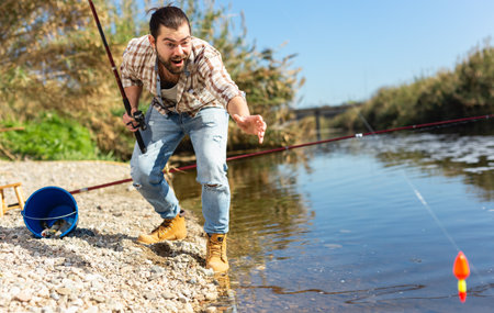 Happy fisherman pulls fish out of the riverの写真素材