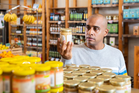 Man reading jar contents on label while shopping in supermarketの写真素材