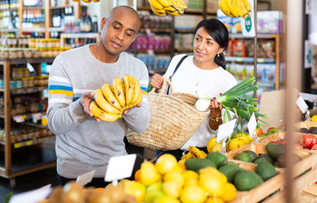 Man and woman picking ripe bananas together at supermarket