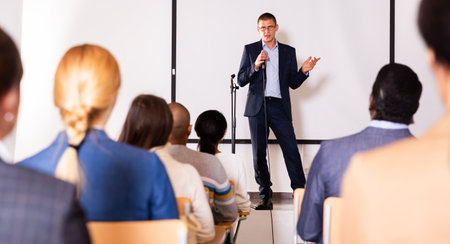 Confident lecturer speaking to businesspeople at seminarの写真素材