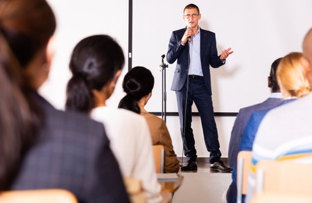 Male coach giving speech at conference hallの写真素材