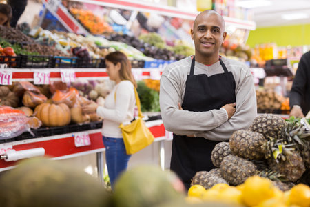 Portrait of employee at grocery supermarket with pineapplesの写真素材