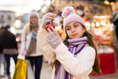 Happy teenage girl demonstrating christmas balls at street marketの写真素材