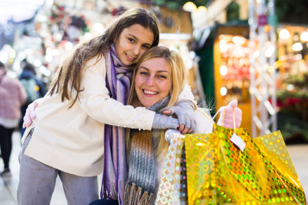 Happy mom and daughter with packages of gifts on street marketの写真素材