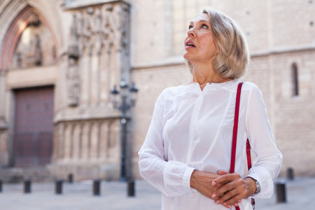 Portrait of mature cheerful woman standing on a old city streetの写真素材
