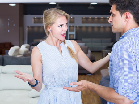 Young female is unpleasantly surprised by price of a sofaの写真素材