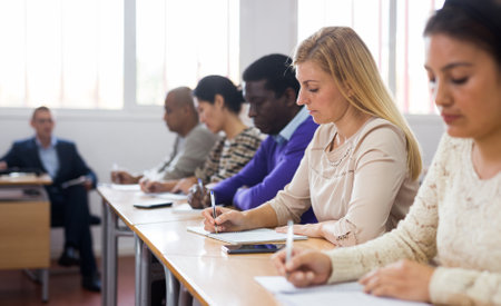 Interested adult woman sitting on lesson in school auditoriumの写真素材