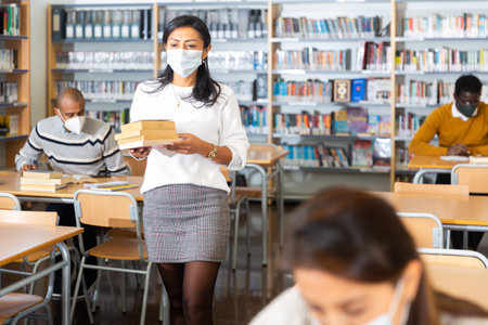 Woman wearing mask studying in public libraryの写真素材