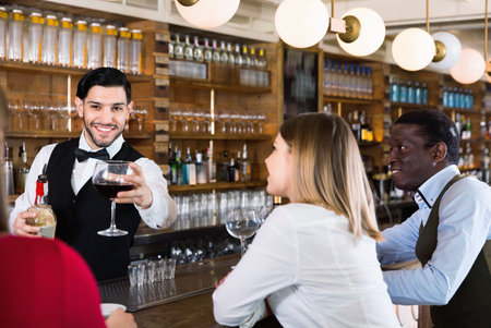 Barman is servicing young people who are relaxing in bar indoor.の写真素材
