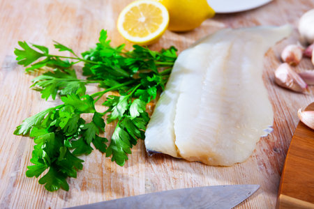 Fillet of raw cod fillet before cooking on wooden background
