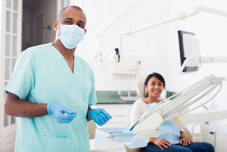 Professional dentist standing with patient backgroundの写真素材
