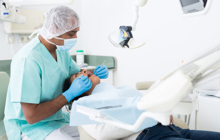 Male dentist treating female patient in dental clinicの写真素材