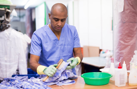 Focused man drycleaner removing spots and stainsの写真素材