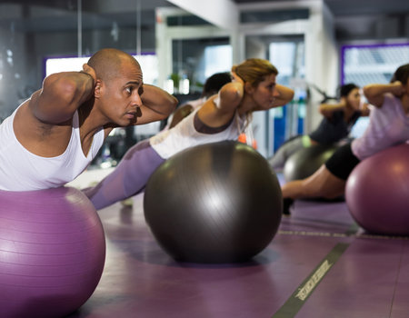 Young man doing exercises with fitness ballの写真素材