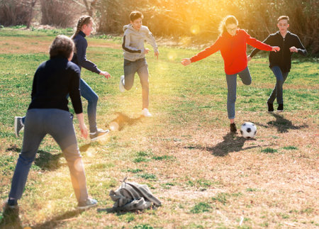 Company of teenagers playing football in park