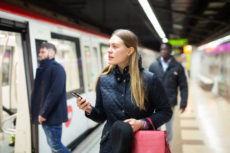 Young woman with phone waiting at subway stationの写真素材
