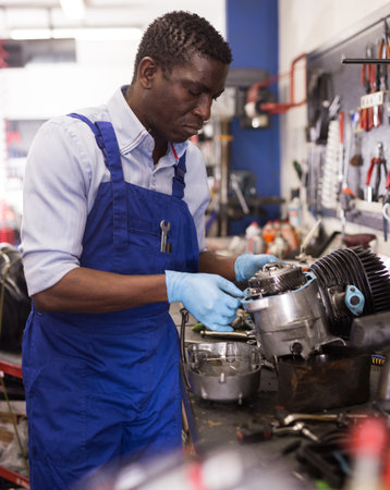 Mechanic in overalls repairing a motorcycle engine in a garageの写真素材