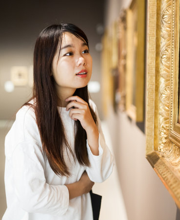 Chinese woman standing in art museum near the paintingの写真素材