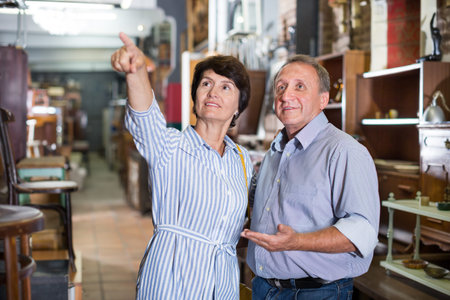 Man with wife are choosing antique furniture