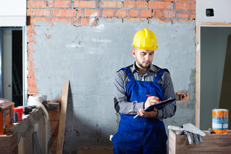 Builder man is writing report about work for client