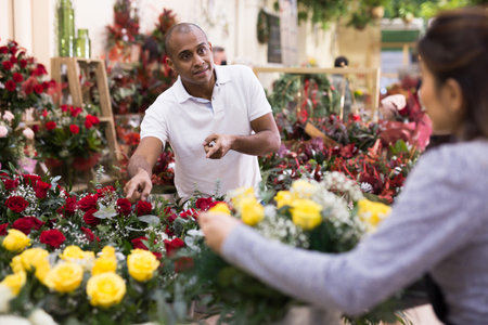 Seller offering gift flower arrangement with roses to male buyerの写真素材