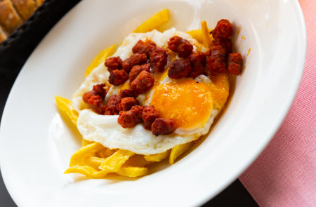 Fried eggs with chistorra sausages and potatoesの写真素材