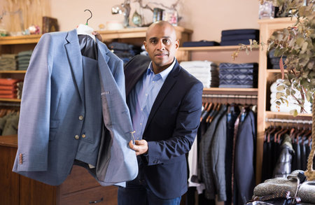 Friendly salesman offering suit in menswear boutique