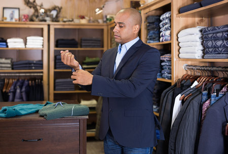 Man choosing suit jacket in clothing store