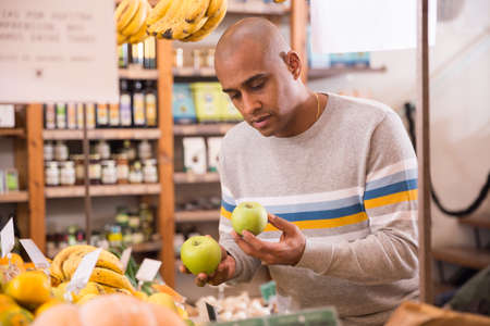 Latin American shopper choosing fresh apples in grocery storeの写真素材