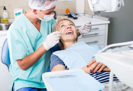 Male dentist treating female patientの写真素材