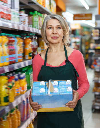 Mature saleswoman in apron arranging productsの写真素材