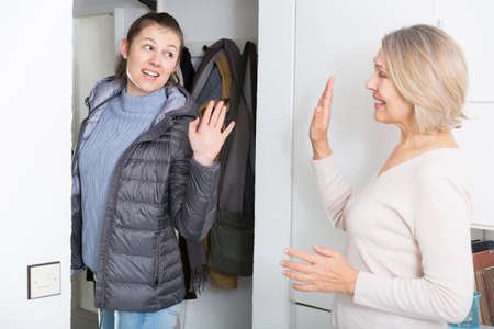 Mom says goodbye to her daughter in the hallway of the apartmentの写真素材