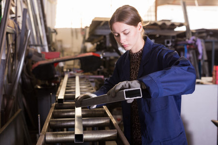 Woman checking metal structures in workshop