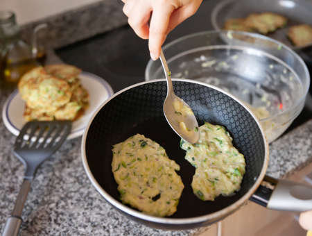 Process of cooked tasty zucchini pancakes in frying panの写真素材