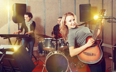 Attractive female soloist playing guitar and singing with her mu