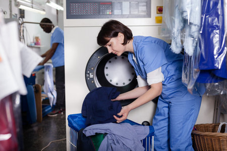 Female worker loading laundry washing machine