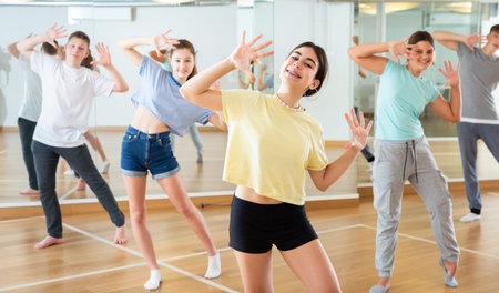 Diligent friendly smiling teenagers learn dance movements
