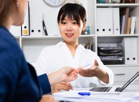 Two businesswomen sitting at desk and working together at officeの写真素材
