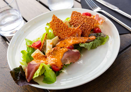 Appetizing Basque salad with sheep cheese, cured ham, romaine salad and tomatoes.の写真素材
