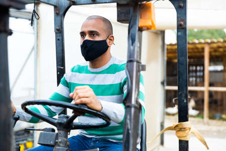 Hispanic man driving a forklift truck during a pandemic.の写真素材