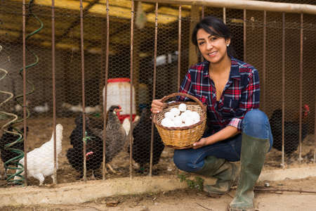Portrait of woman farmer with basket of chicken eggsの写真素材