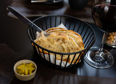 Sliced fresh baked artisan bread with butter in serving basket