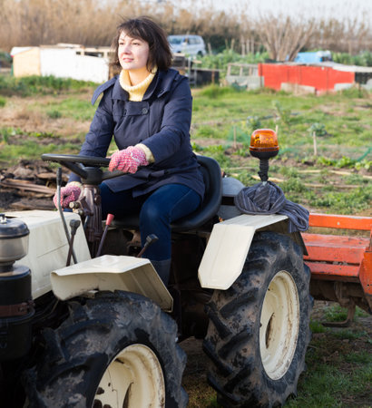 Positive woman working on small farm tractorの写真素材